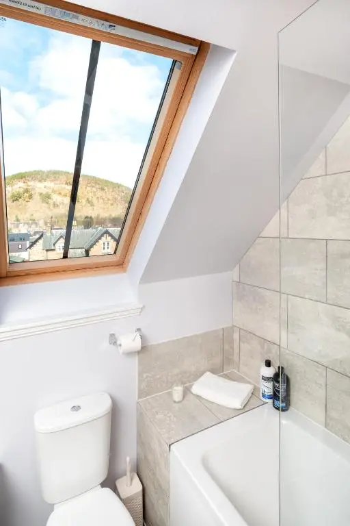a bathroom with a toilet and a window at Historic Village, Rare Find, Amazing Views in Ballater