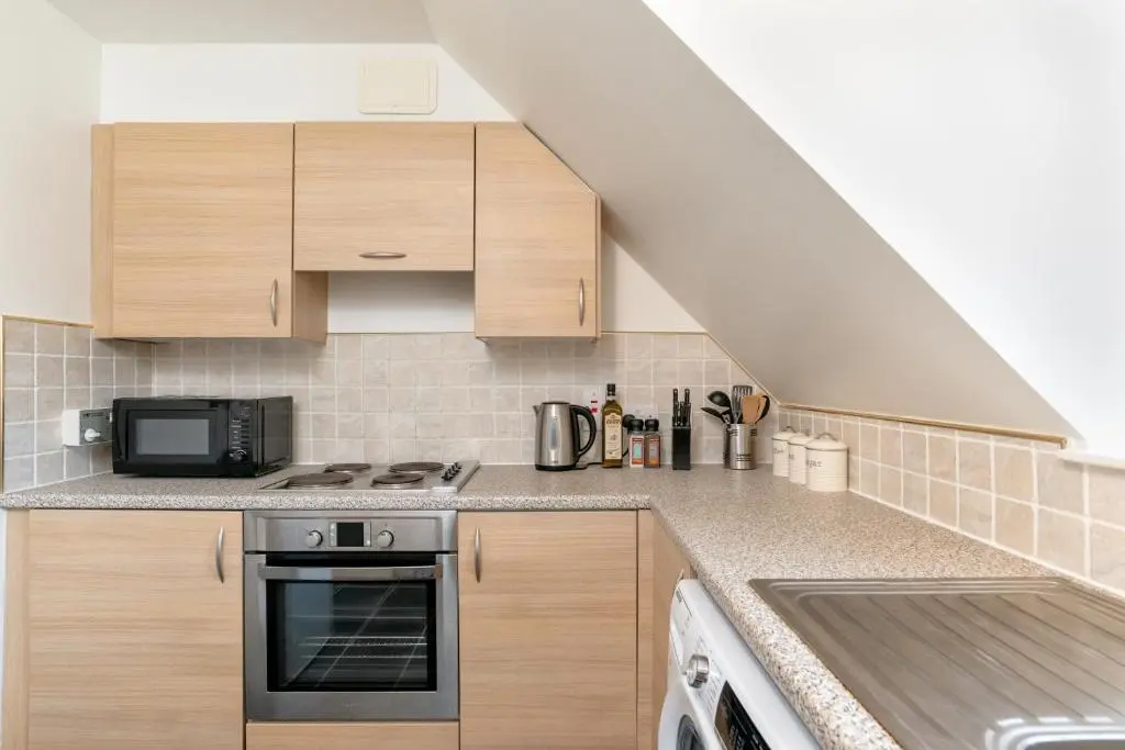 a kitchen with wooden cabinets and a stove top oven at Historic Village, Rare Find, Amazing Views in Ballater
