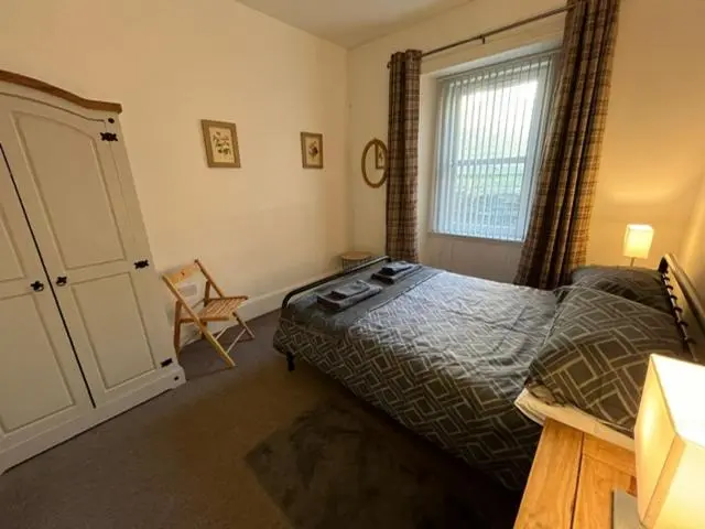 a bedroom with a bed and a window and a chair at Centrally located 2 bed modern flat with harbour views in Wick