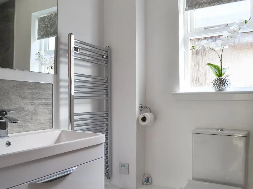 a bathroom with a sink and a toilet and a window at Uaine Cottage in Aviemore
