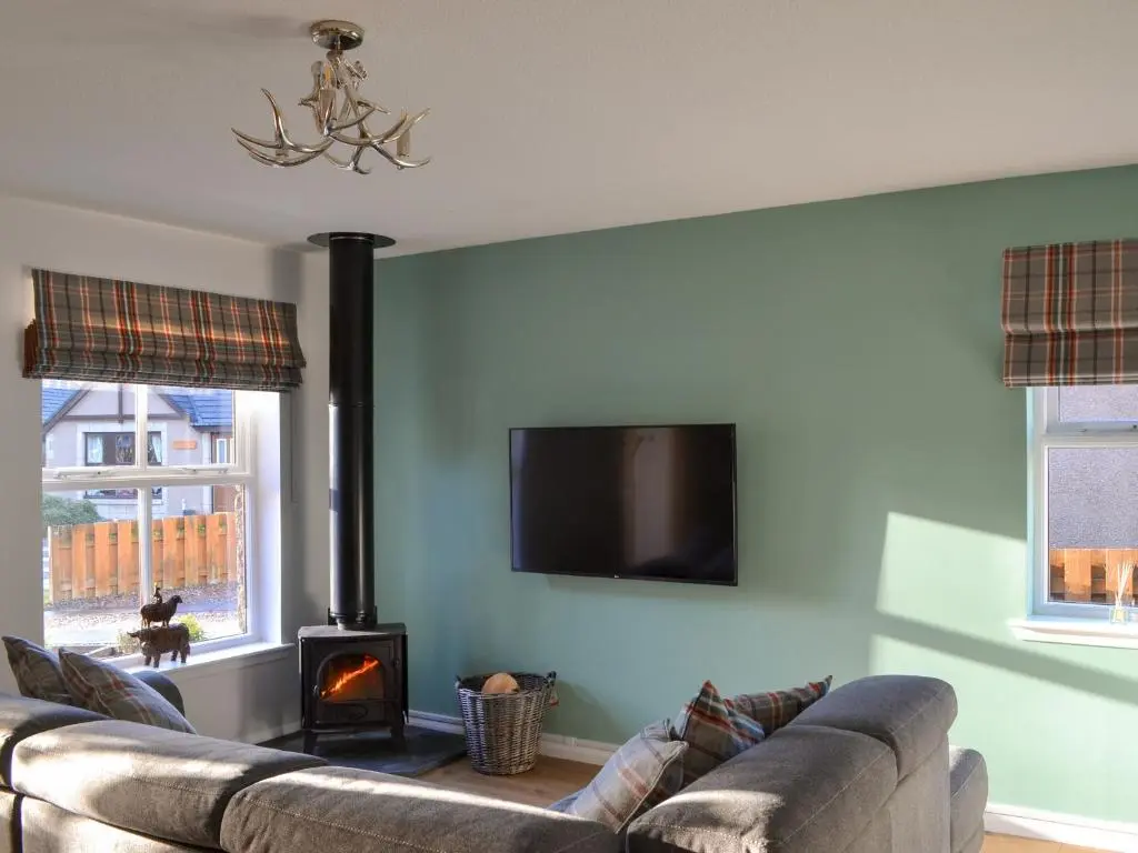 a living room with two couches and a flat screen tv at Uaine Cottage in Aviemore