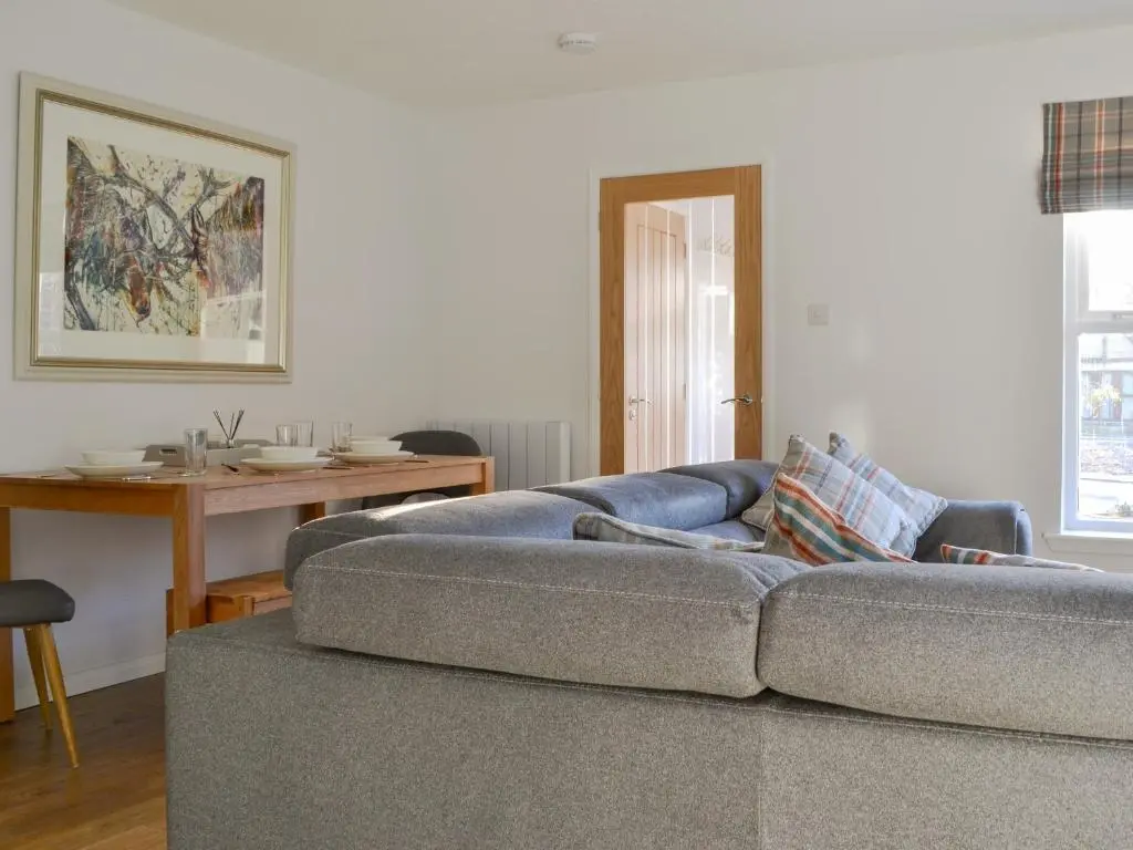 a living room with a couch and a table at Uaine Cottage in Aviemore