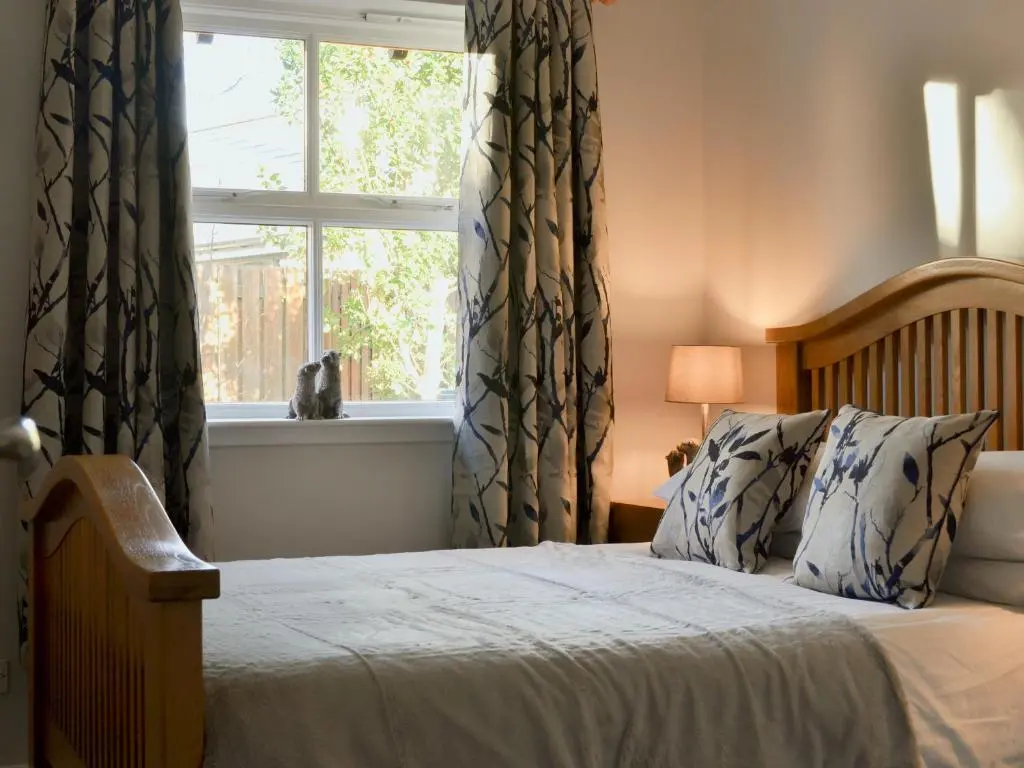 a bedroom with a bed and a window with curtains at Uaine Cottage in Aviemore