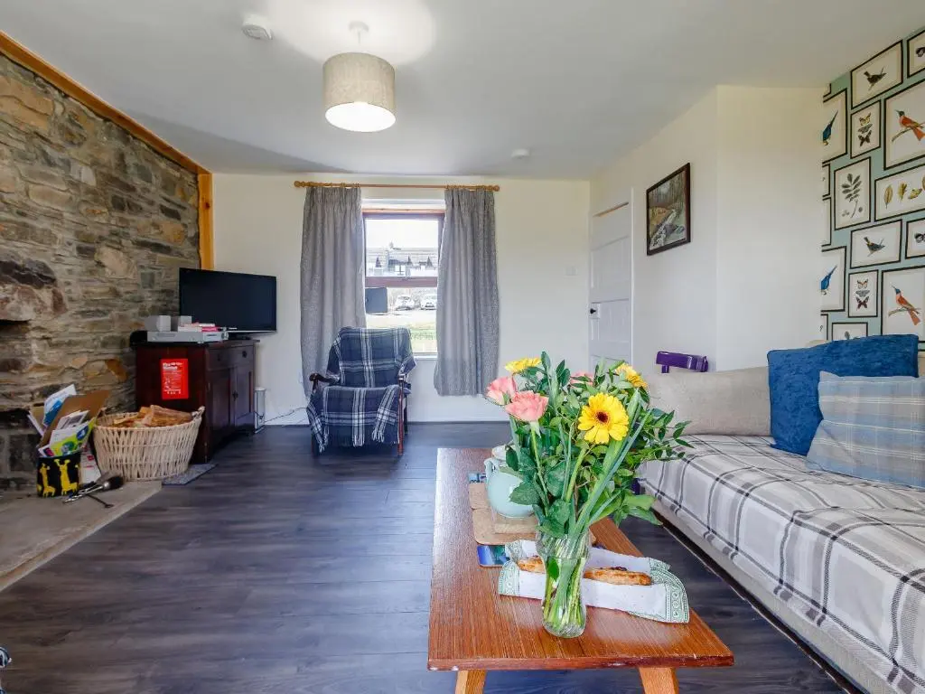 a living room with a couch and a table with flowers at 19 South Street in Grantown on Spey
