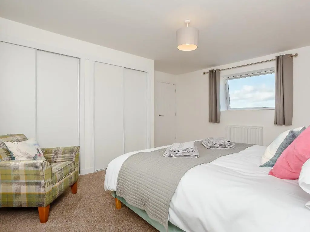 a bedroom with a bed and a chair in it at Knocknahighle in Cromdale