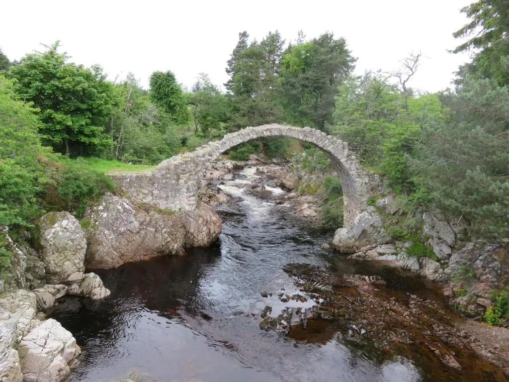 an old stone bridge over a river in a forest at Bankhouse B&B in Aberlour