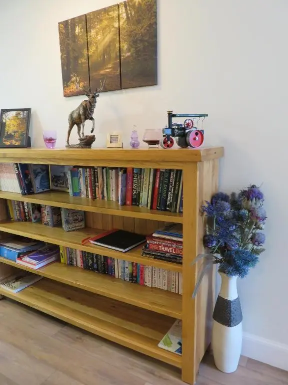 a book shelf with books and a vase of flowers at Bankhouse B&B in Aberlour
