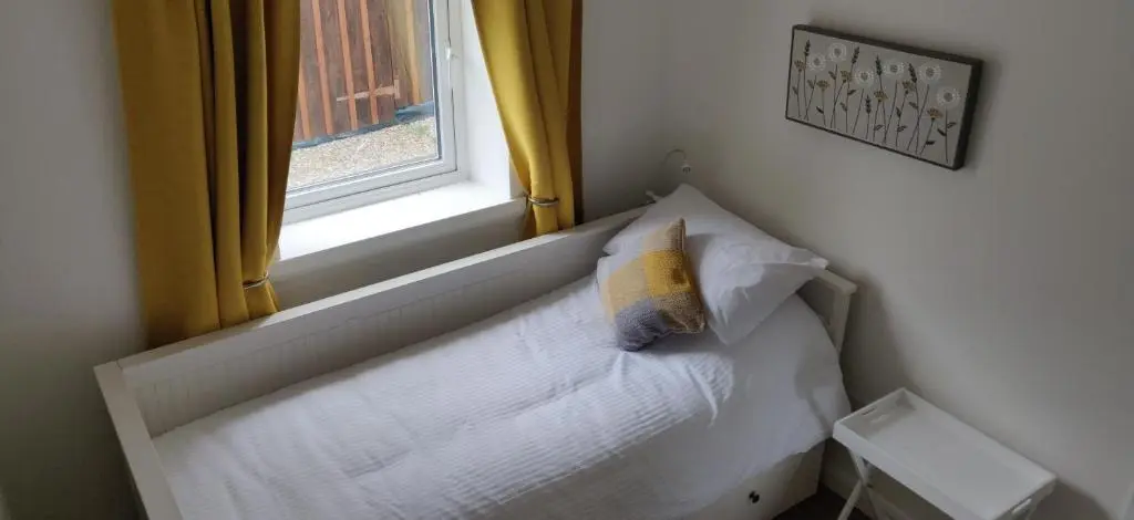 a bed with a pillow on it next to a window at 4-Bed Cottage in Portknockie Near Cullen Moray in Portknockie
