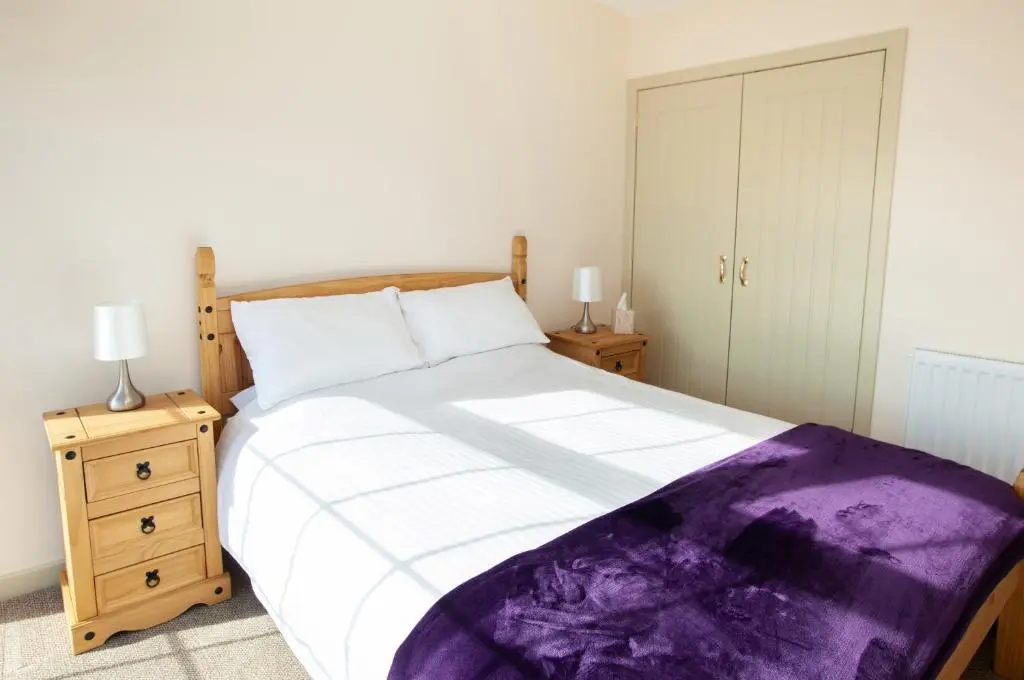 a bedroom with a bed with a purple blanket on it at Balintore Inn in Balintore