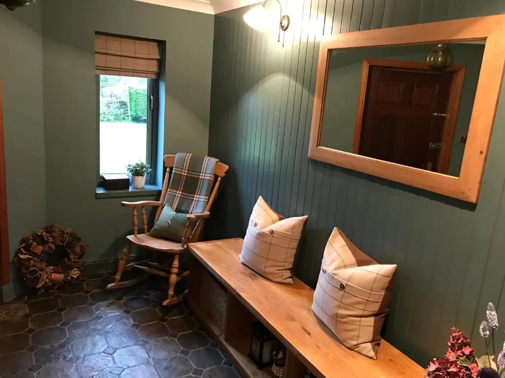 a room with a bench with pillows and a mirror at Highfield House in Dornoch