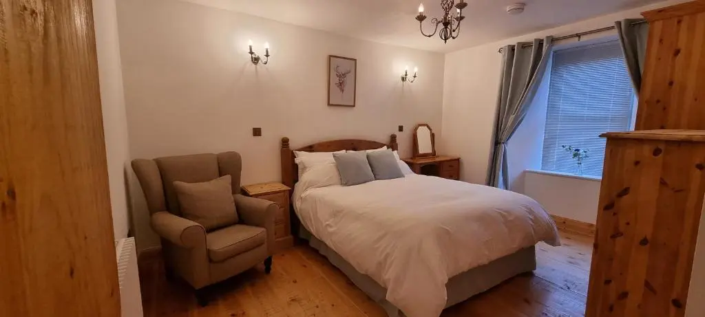 a bedroom with a bed and a chair at The Coal Office Aberlour in Aberlour