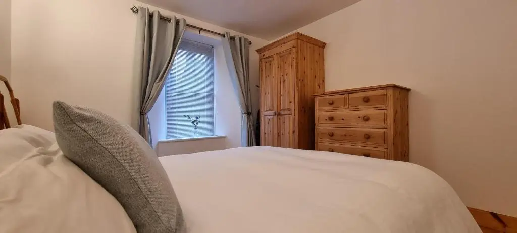 a bedroom with a bed and a dresser and a window at The Coal Office Aberlour in Aberlour
