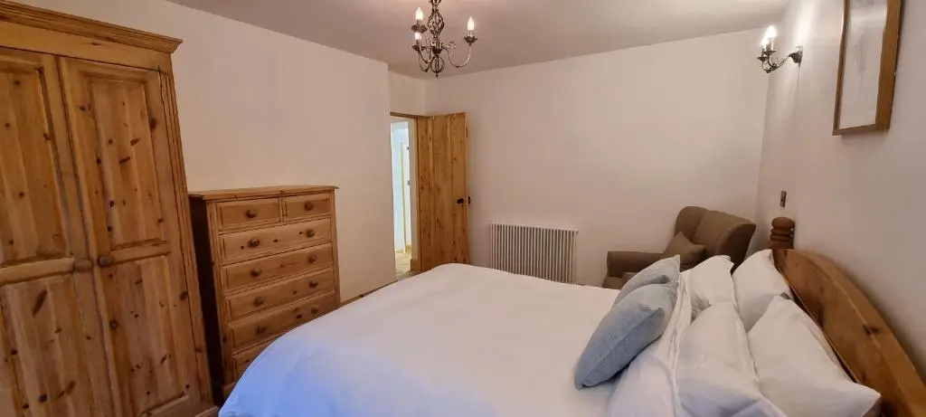 a bedroom with a white bed and a wooden dresser at The Coal Office Aberlour in Aberlour