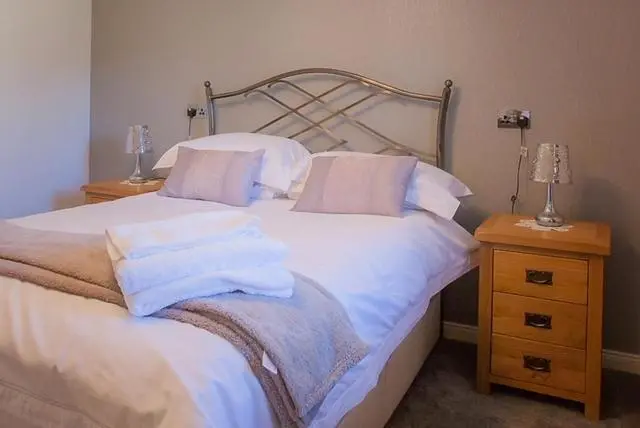 a bedroom with a bed with white sheets and pillows at 2 Bed Blackburn Village Apt With Wifi & Parking in Aberdeen