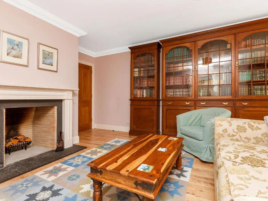 a living room with a fireplace and a table at Rowan House in Inveran
