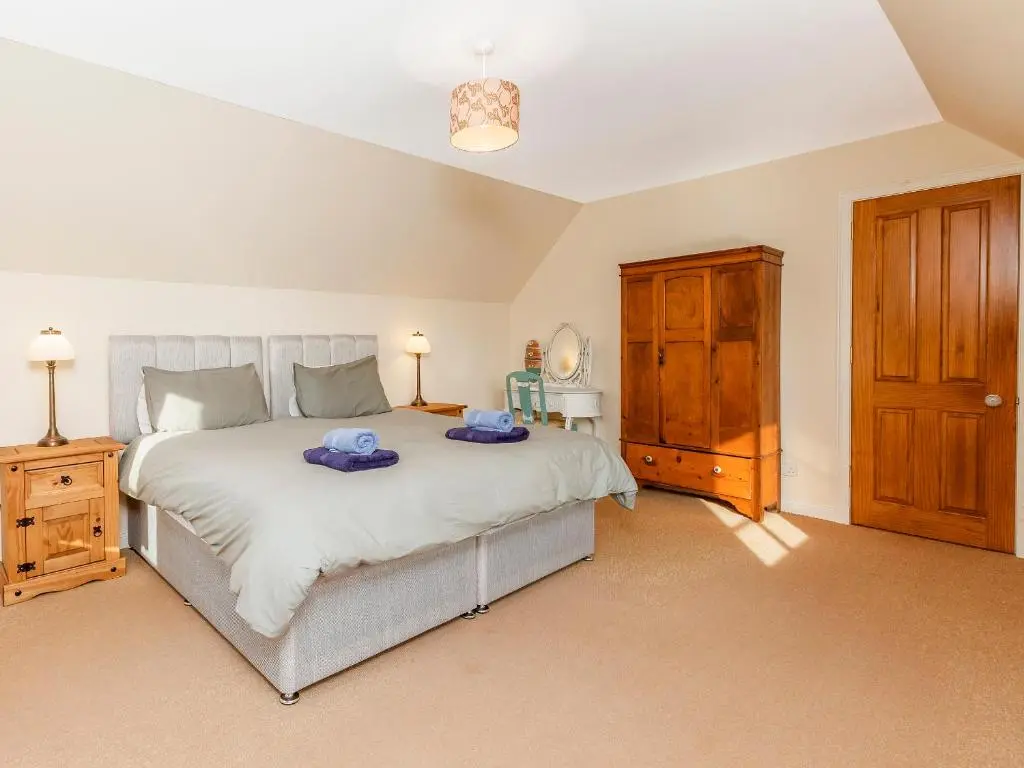 a bedroom with a large bed and a wooden cabinet at Rowan House in Inveran