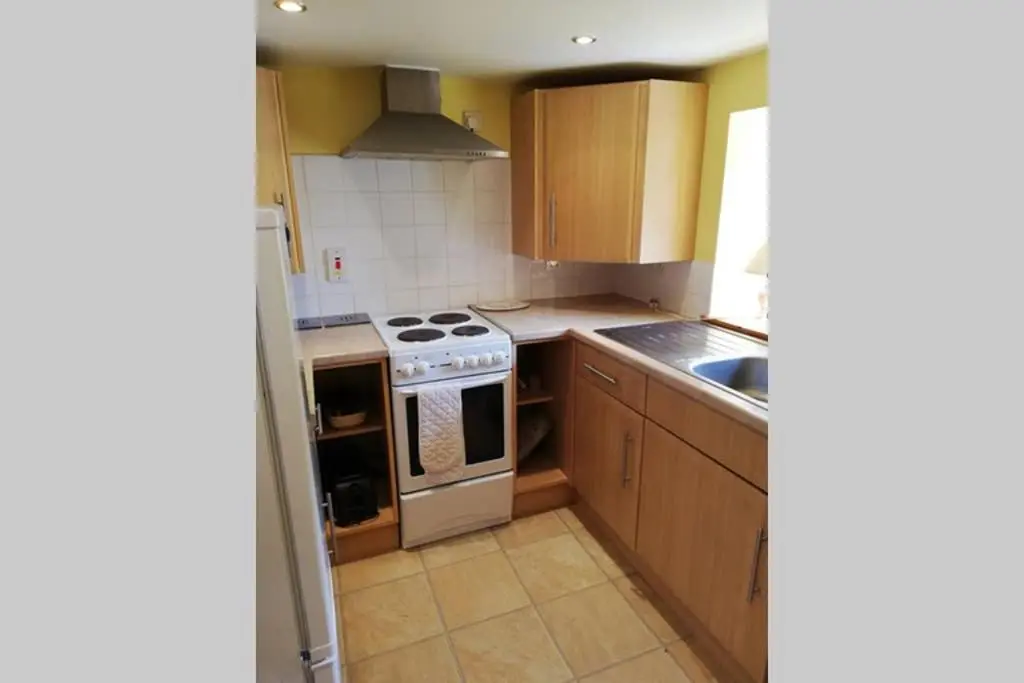 a kitchen with wooden cabinets and a stove top oven at Boghead Cottage: Holiday Cottage in Royal Deeside in Banchory