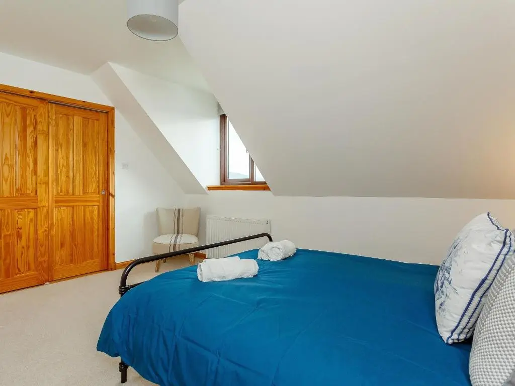 a bedroom with a blue bed with two towels on it at The Big Hoose in Achnahanat