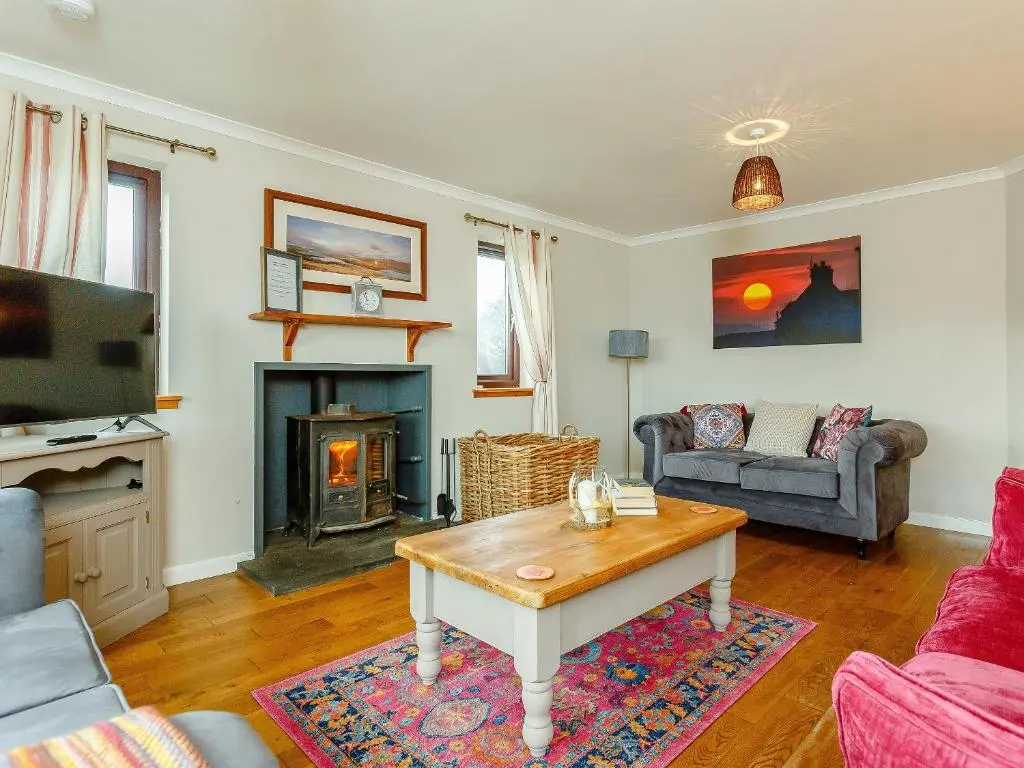 a living room with a table and a fireplace at The Big Hoose in Achnahanat