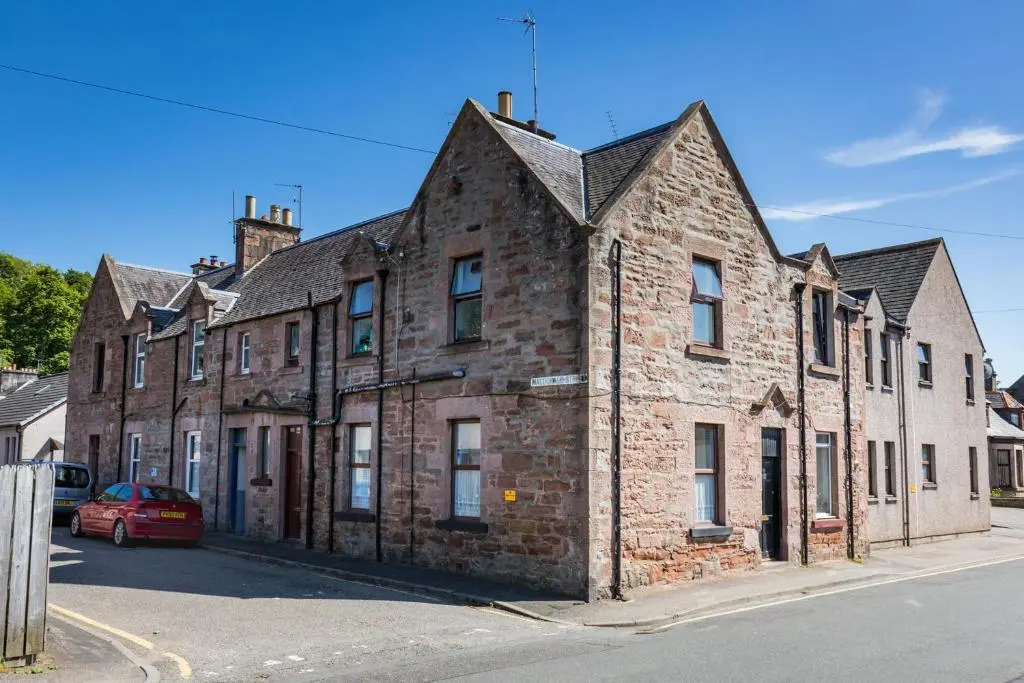an old brick building on the corner of a street at Macdonald Street Snug in Inverness
