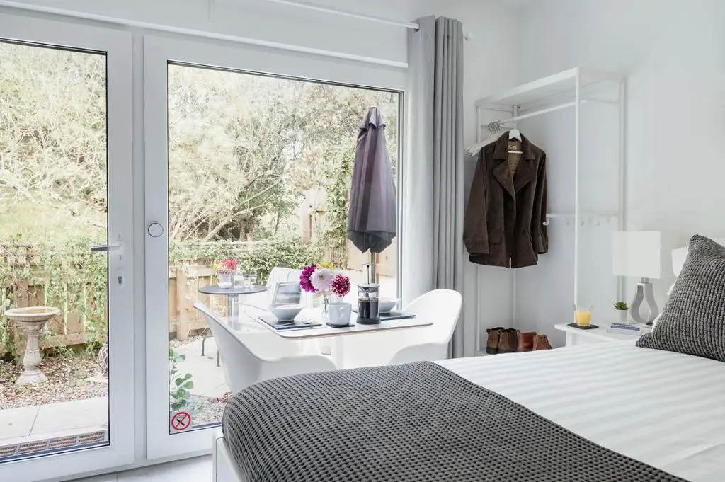 a bedroom with a bed and a table and a sliding glass door at Siskin Guest Suite in Kinrara