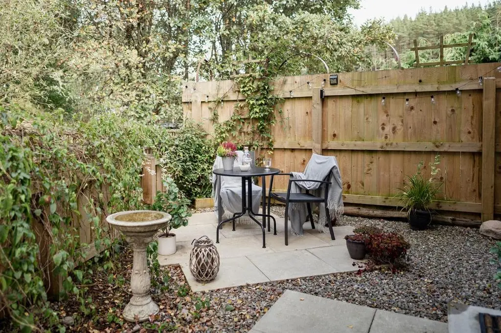 a patio with a table and chairs in a garden at Siskin Guest Suite in Kinrara