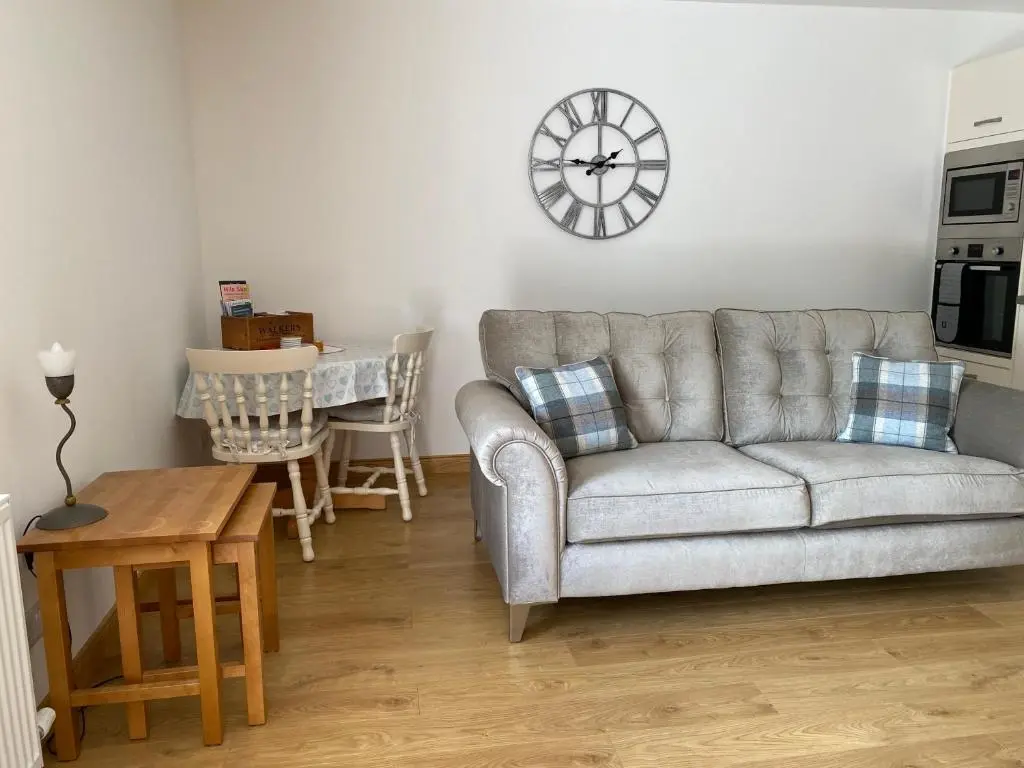 a living room with a couch and a clock on the wall at The Den in Stuartfield