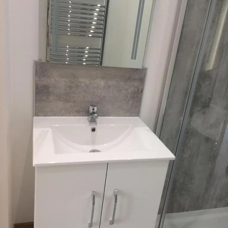 a bathroom with a white sink and a shower at The Den in Stuartfield