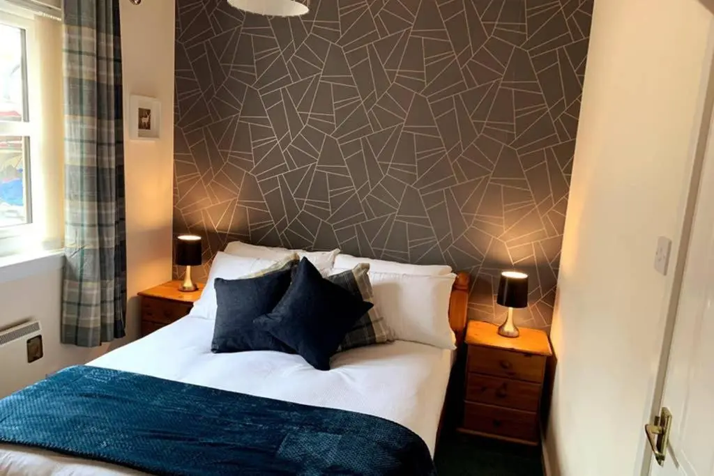 a bedroom with a bed and a wall at Cairngorm Cottage in Aviemore