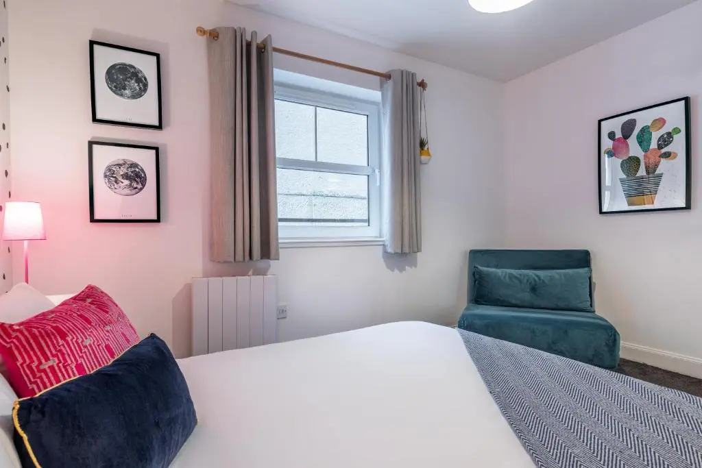 a bedroom with a bed and a blue chair at Ness Central in Inverness