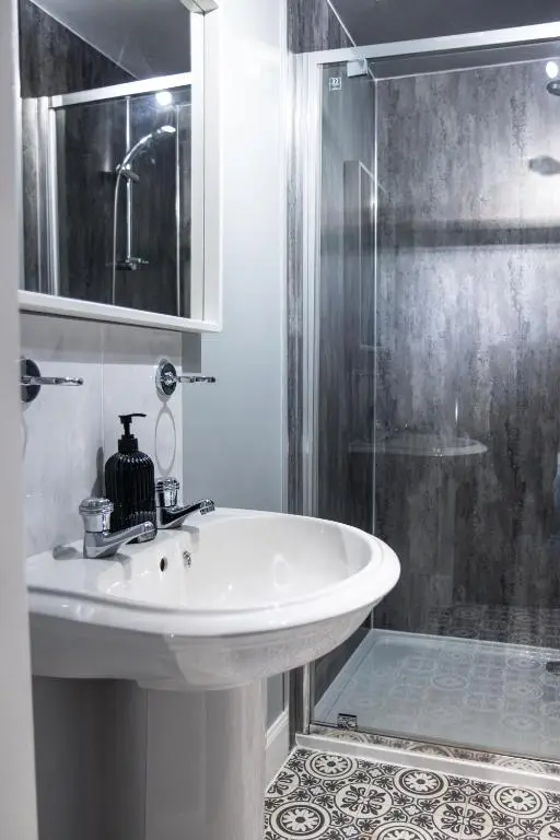 a white bathroom with a sink and a shower at Ness Central in Inverness