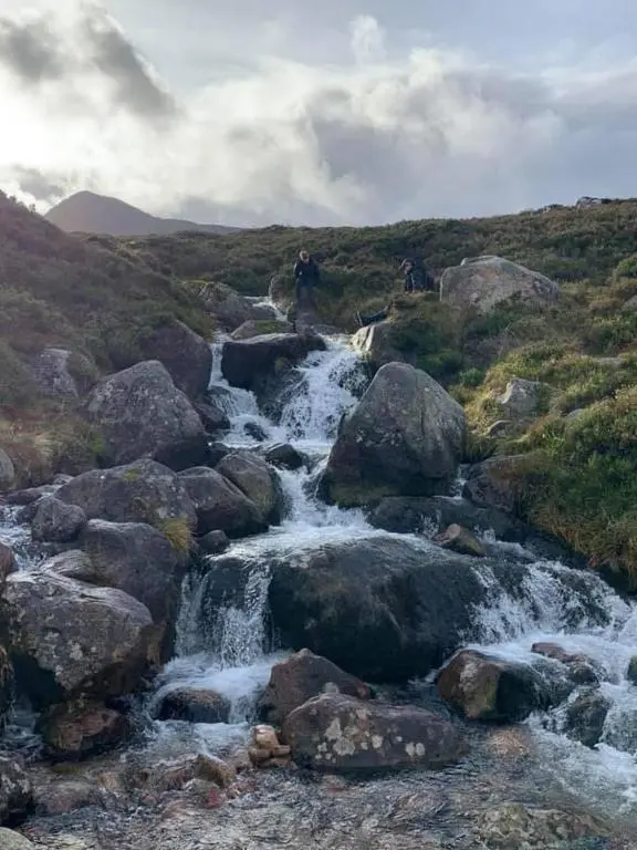 a stream of water in a field with rocks at The One - Chalet in the Cairngorms in Boat of Garten