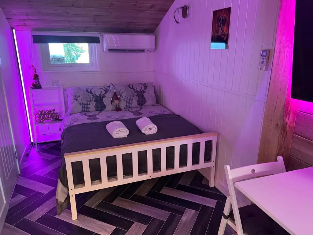 a small room with a bed in a purple room at Royal Snug & Wee Snug Cabins in Kincardine O\u02bcNeil
