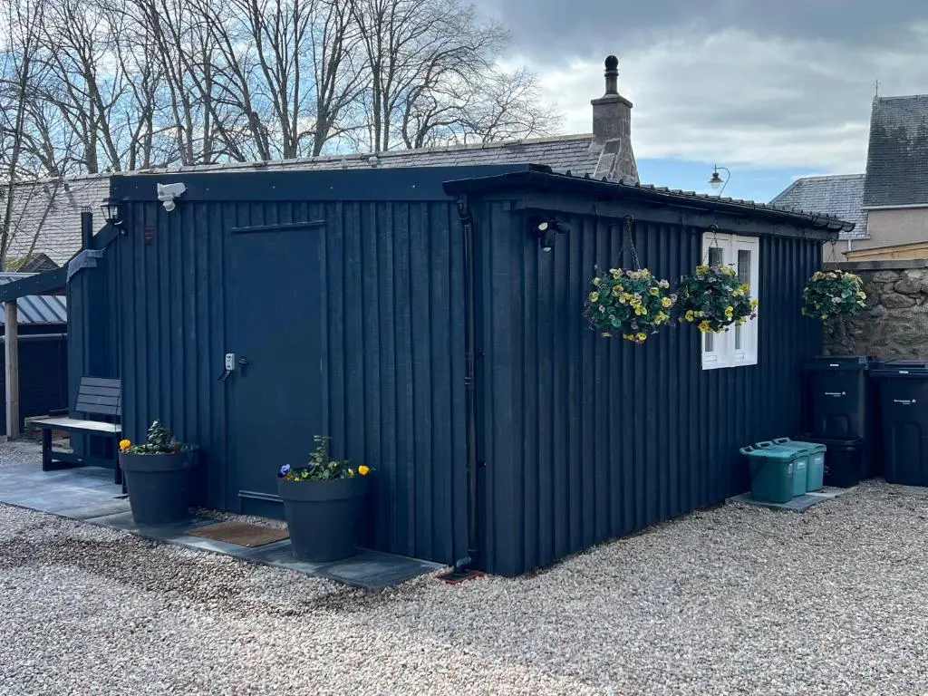 a black shed with potted plants on it at Royal Snug & Wee Snug Cabins in Kincardine O\u02bcNeil