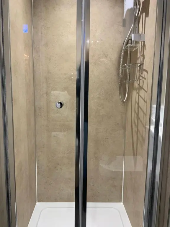 a shower with a glass door in a bathroom at Royal Snug & Wee Snug Cabins in Kincardine O\u02bcNeil