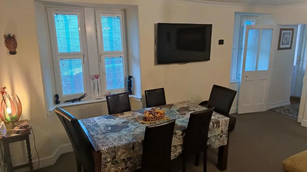 a dining room with a table and chairs and a television at Dunvegan House in Helmsdale