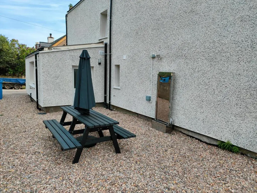 a green umbrella sitting next to a building at Dunvegan House in Helmsdale