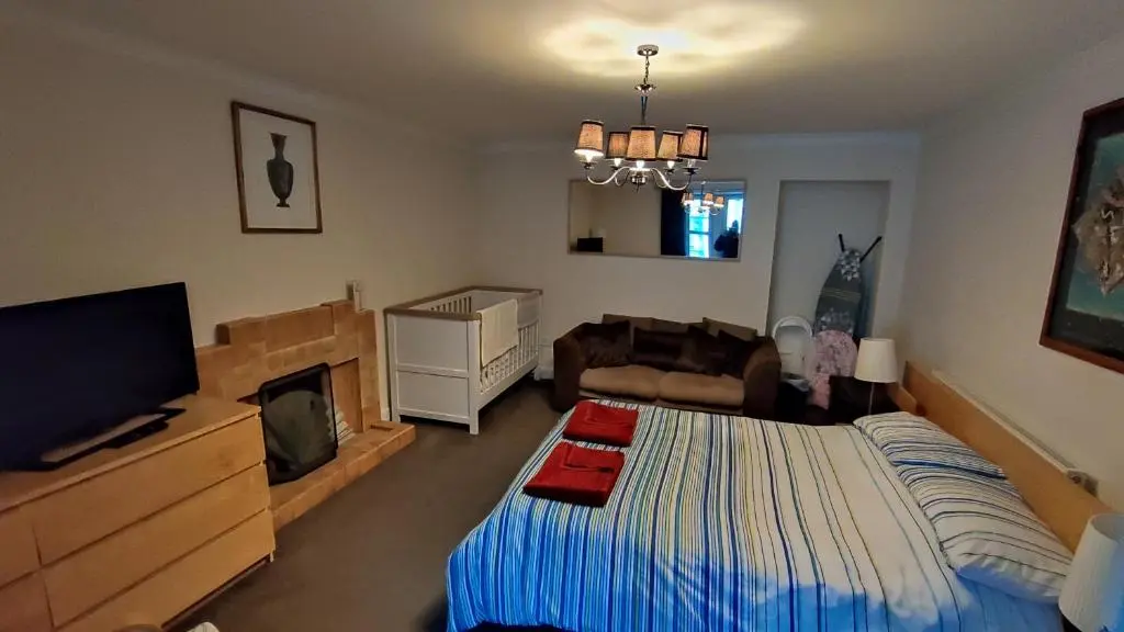 a bedroom with a bed and a couch and a television at Dunvegan House in Helmsdale