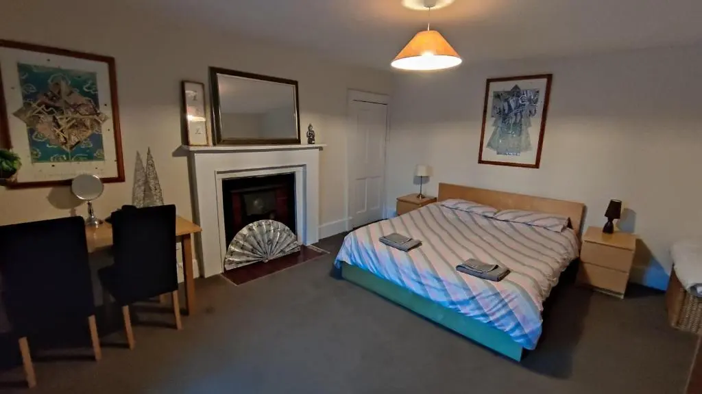 a bedroom with a bed and a fireplace at Dunvegan House in Helmsdale
