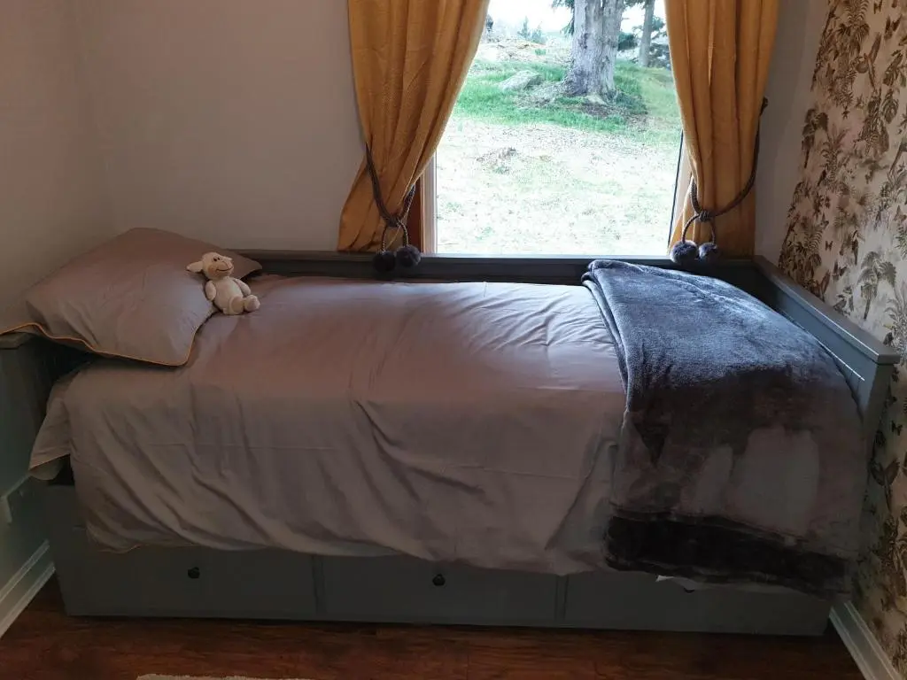 a teddy bear sitting on a bed next to a window at Craigbreck Farm Cottage in North Kessock