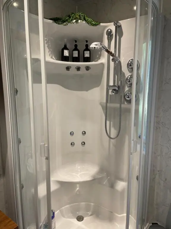 a shower with bottles on a shelf in a bathroom at Craigbreck Farm Cottage in North Kessock