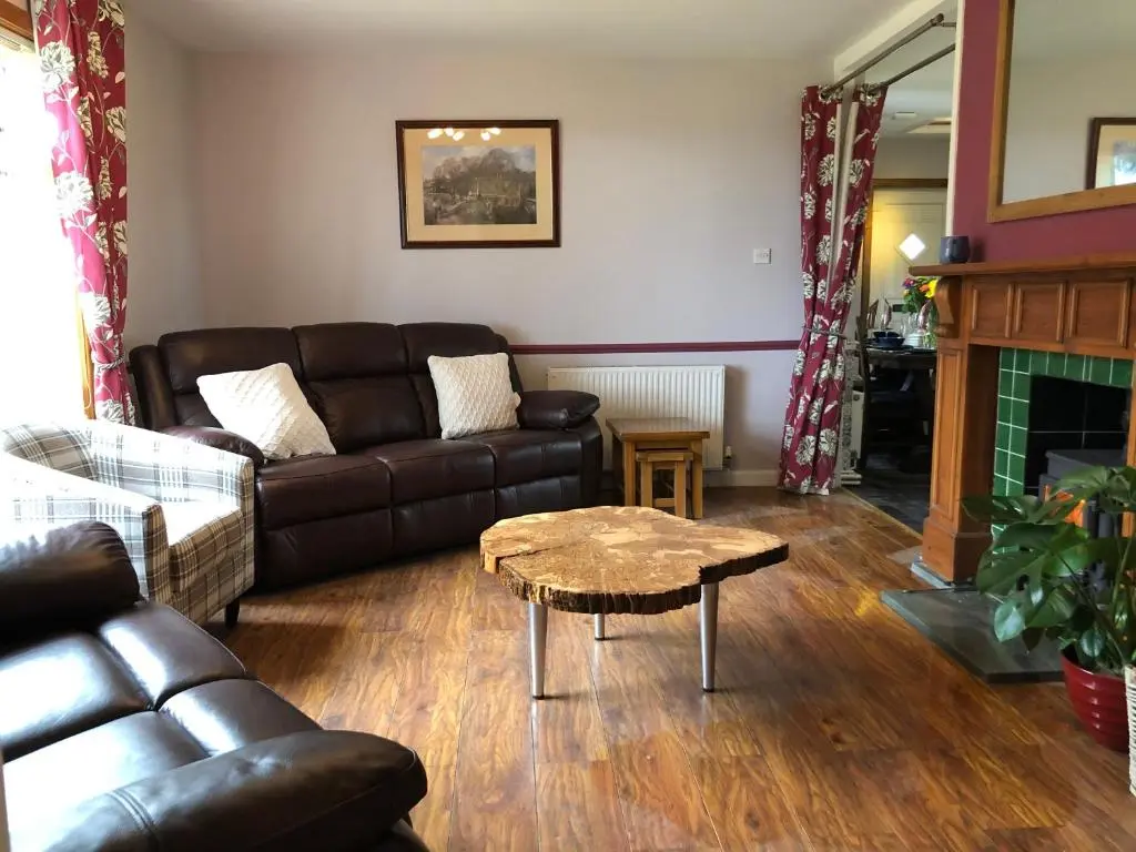 a living room with a leather couch and a coffee table at Craigbreck Farm Cottage in North Kessock