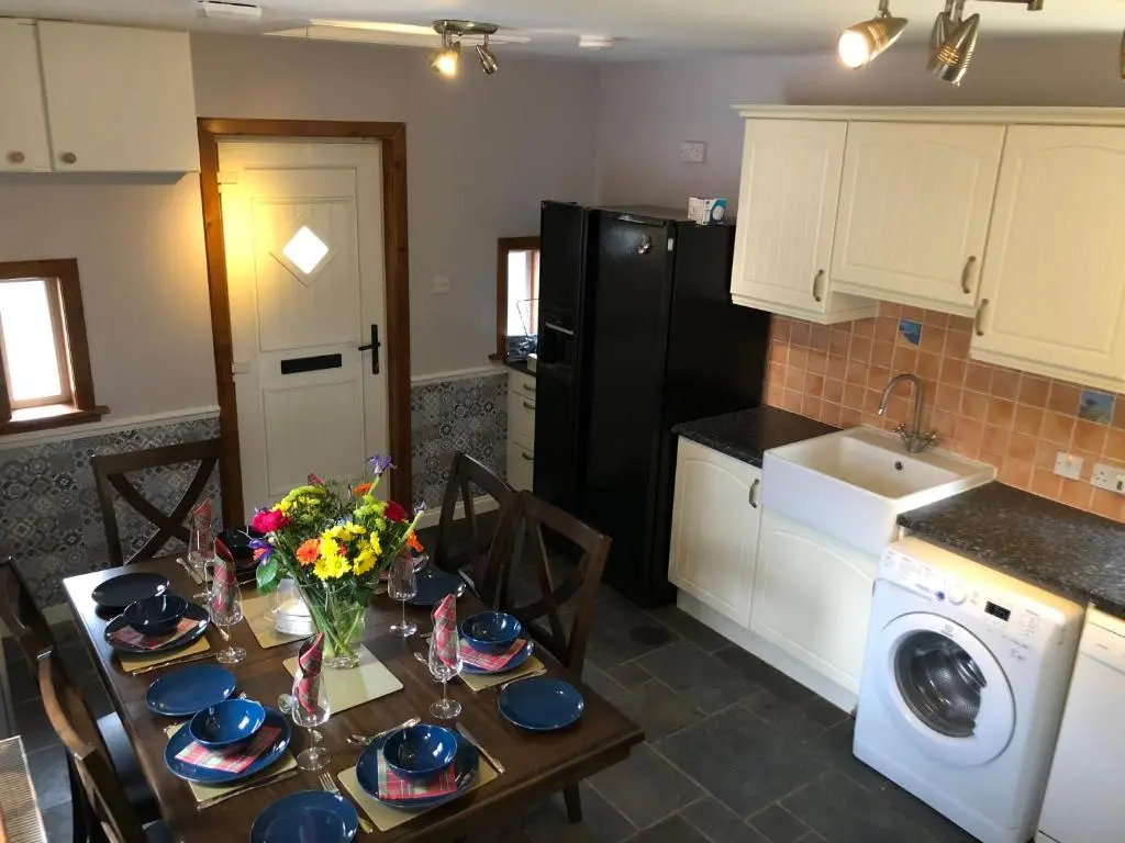 a kitchen with a table with plates and flowers on it at Craigbreck Farm Cottage in North Kessock