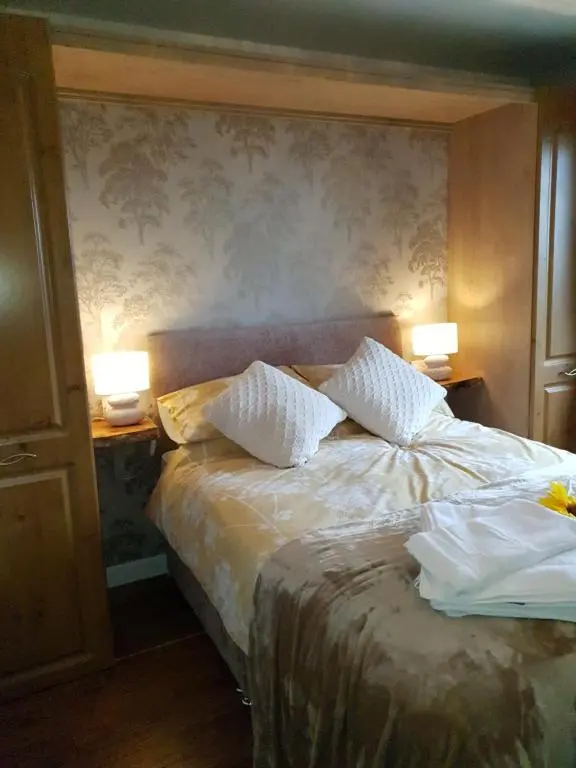a bedroom with a bed with two lamps on it at Craigbreck Farm Cottage in North Kessock