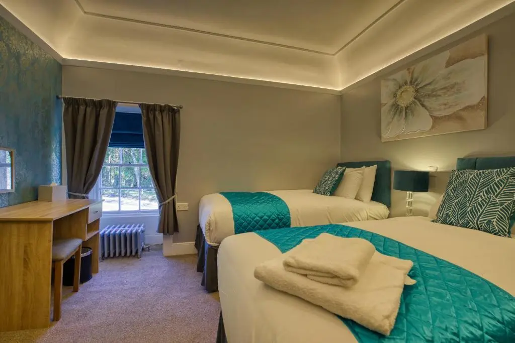 a hotel room with two beds and a desk at Golspie Inn in Backies