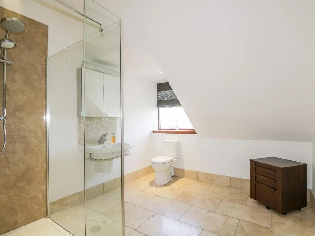 a bathroom with a toilet and a glass shower at Orrinside in Muir of Ord