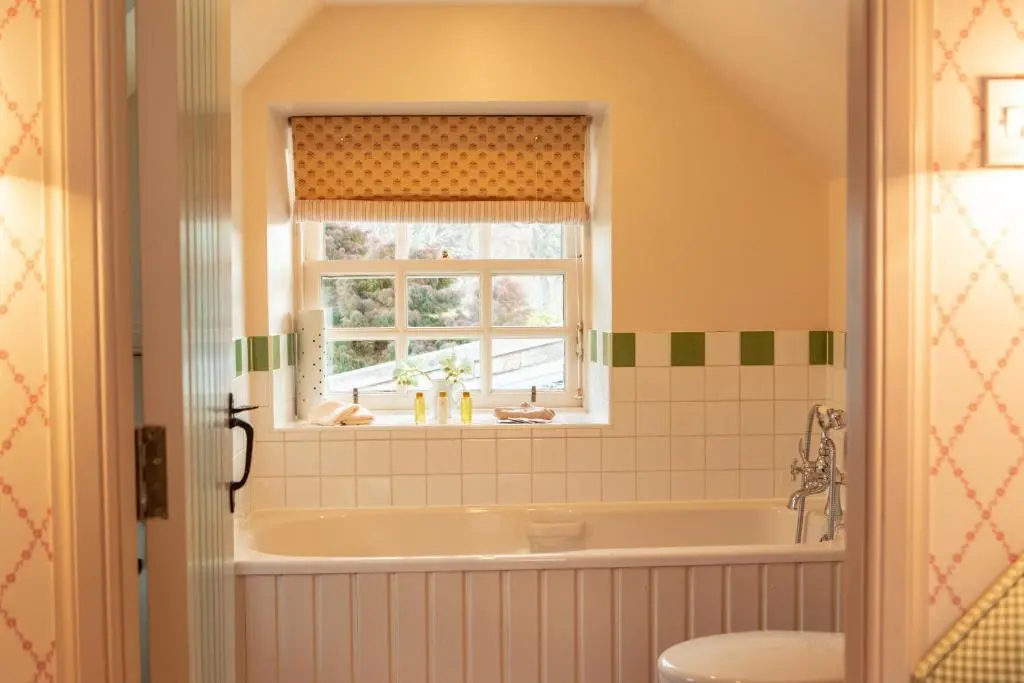 a bathroom with a tub and a window at Balnagown Estates Gardener's Cottage in Kildary