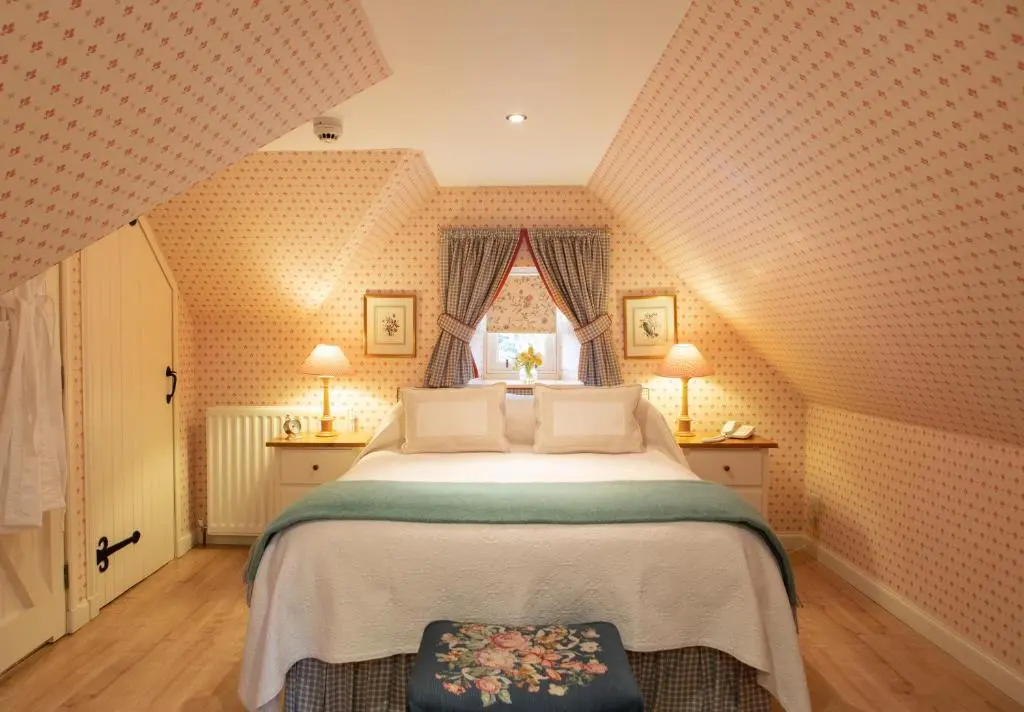 a bedroom with a large bed and a window at Balnagown Estates Gardener's Cottage in Kildary