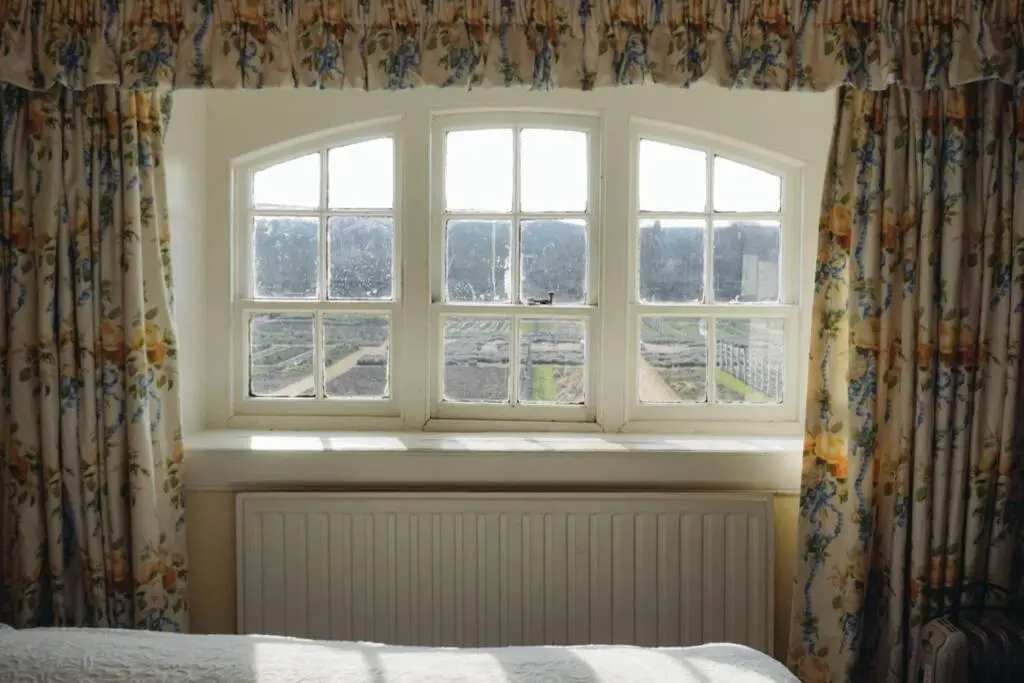 a bedroom with two windows with curtains and a bed at Garden Cottage, Fochabers in Fochabers