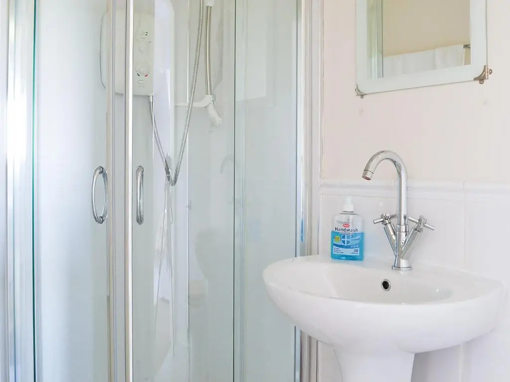 a white bathroom with a sink and a shower at Brighton House in Nairn
